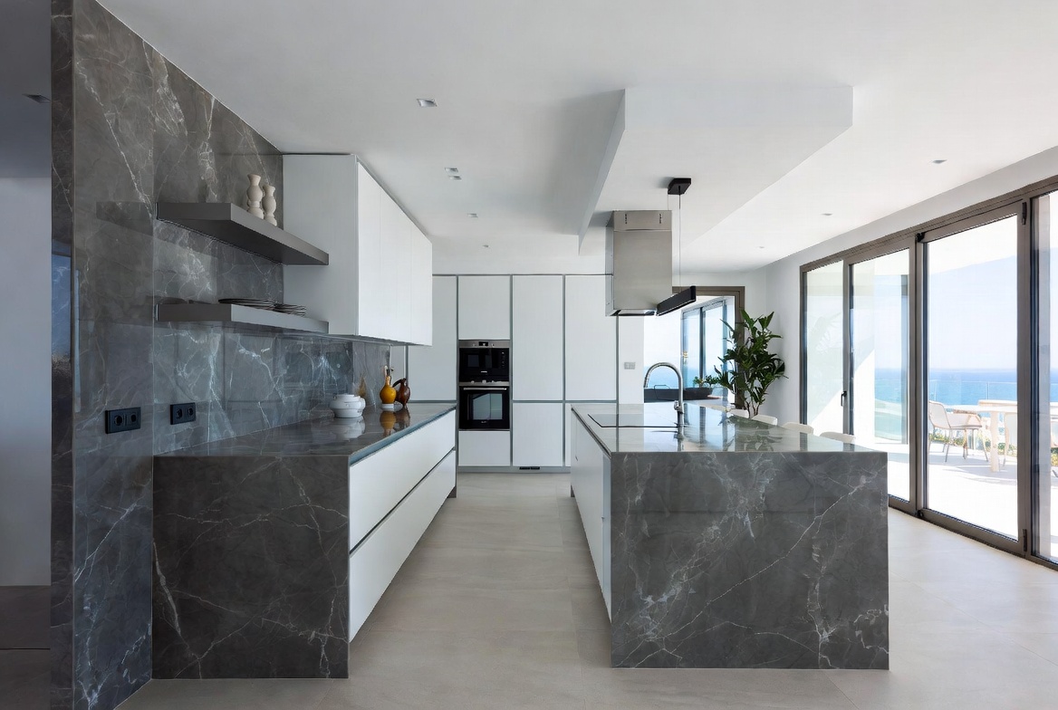 Diseño de cocina minimalista de lujo con isla central de mármol y vistas al mar en Marbella, por Design & Style.